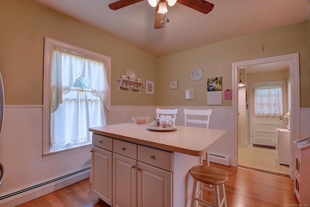 32 Columbus St, East Hartford, CT 06108 - kitchen featuring a baseboard heating unit, a breakfast bar, wainscoting, a ceiling fan, and light countertops