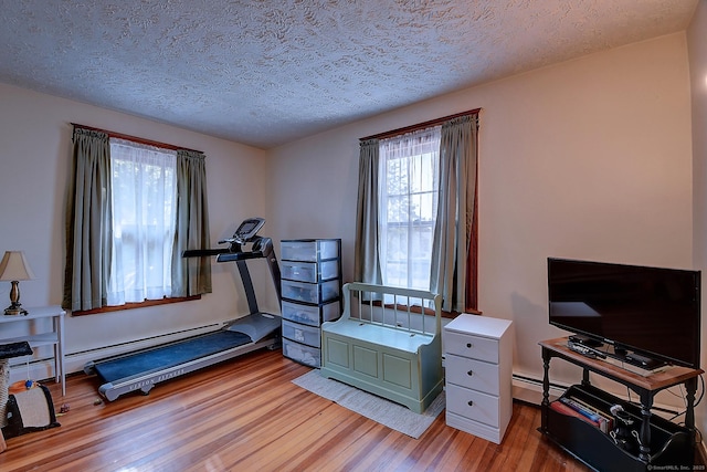 32 Columbus St, East Hartford, CT 06108 - exercise room with wood finished floors, a textured ceiling, and a baseboard radiator