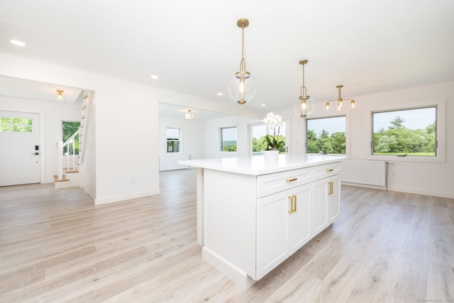 1669 Rte 169, Woodstock, CT 06281 - kitchen featuring radiator, light countertops, light wood-style flooring, white cabinetry, and a center island