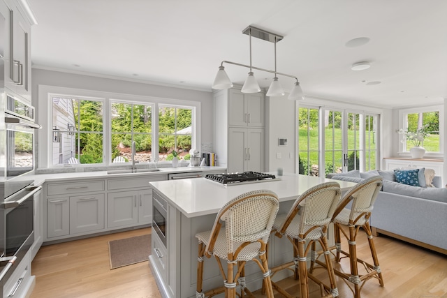 289 Wahackme Rd, New Canaan, CT 06840 - kitchen with appliances with stainless steel finishes, light countertops, a kitchen island, light wood-style flooring, and open floor plan