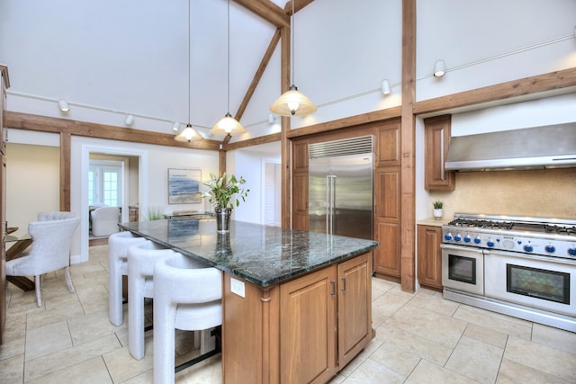 29 Bradley Rd, Weston, CT 06883 - kitchen featuring premium appliances, light tile patterned flooring, brown cabinets, wall chimney exhaust hood, and high vaulted ceiling