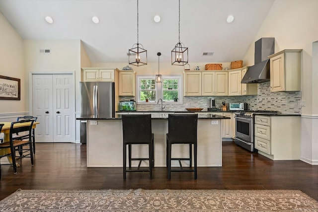 311 Wilton Rd E, Ridgefield, CT 06877 - kitchen featuring stainless steel appliances, wall chimney range hood, cream cabinets, a kitchen island, and a kitchen breakfast bar