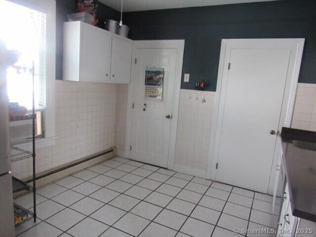 76 Porter St, Bridgeport, CT 06606 - kitchen featuring tile walls, wainscoting, light tile patterned floors, white cabinets, and a baseboard radiator
