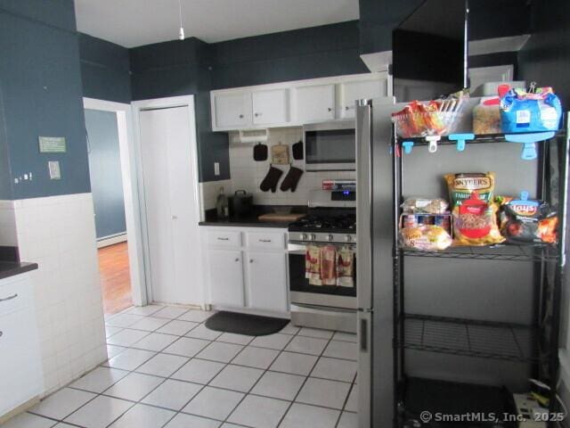 76 Porter St, Bridgeport, CT 06606 - kitchen with appliances with stainless steel finishes, dark countertops, white cabinets, a baseboard heating unit, and light tile patterned floors
