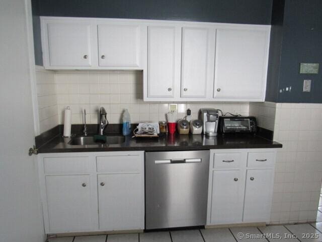 76 Porter St, Bridgeport, CT 06606 - kitchen featuring stainless steel dishwasher, white cabinets, dark countertops, decorative backsplash, and light tile patterned flooring
