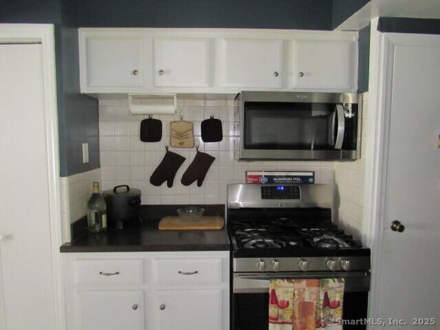 76 Porter St, Bridgeport, CT 06606 - kitchen with appliances with stainless steel finishes, tasteful backsplash, dark countertops, and white cabinets