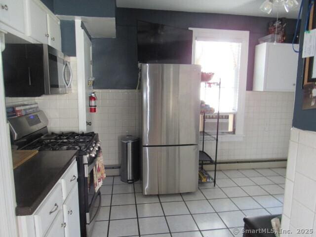 76 Porter St, Bridgeport, CT 06606 - kitchen featuring stainless steel appliances, tile walls, light tile patterned floors, white cabinets, and dark countertops