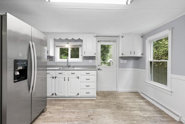 159 Bolton Rd, Vernon, CT 06066 - kitchen featuring stainless steel fridge, a baseboard radiator, white cabinetry, light wood finished floors, and wainscoting