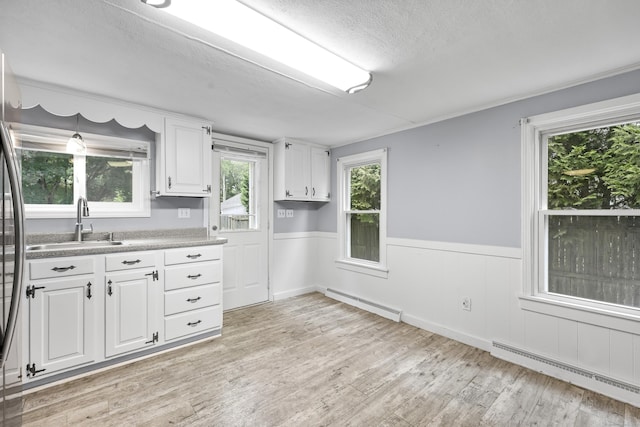 159 Bolton Rd, Vernon, CT 06066 - kitchen featuring baseboard heating, light wood-style floors, white cabinets, a textured ceiling, and wainscoting