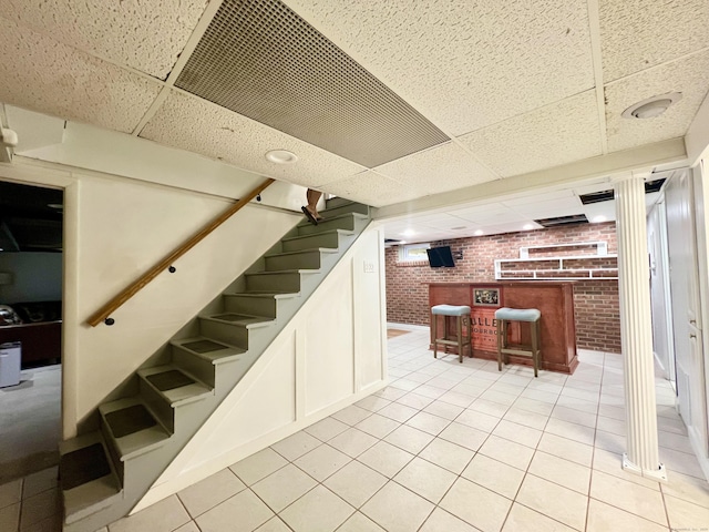 65 Patchen St, Stratford, CT 06615 - finished below grade area featuring brick wall, a paneled ceiling, a dry bar, stairs, and light tile patterned floors