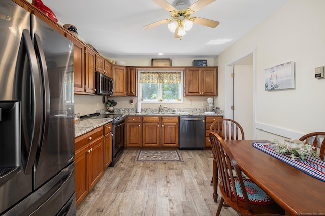 138 S Shore Rd, Killingly, CT 06241 - kitchen featuring appliances with stainless steel finishes, light wood-style flooring, brown cabinets, light stone counters, and a ceiling fan