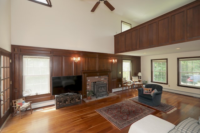 9 River Bend Ln, Windsor, CT 06095 - living area featuring a baseboard radiator, a high ceiling, hardwood / wood-style flooring, ceiling fan, and a wood stove