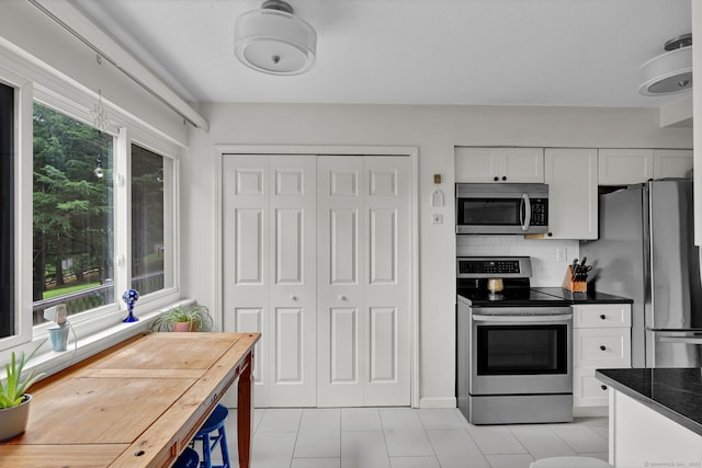 148 Conestoga Way Unit 148, Glastonbury, CT 06033 - kitchen featuring stainless steel appliances, light tile patterned floors, dark countertops, white cabinets, and decorative backsplash