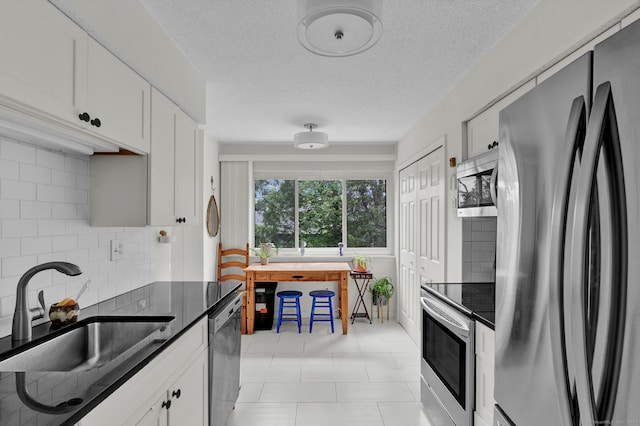 148 Conestoga Way Unit 148, Glastonbury, CT 06033 - kitchen with stainless steel appliances, decorative backsplash, white cabinetry, light tile patterned floors, and a textured ceiling