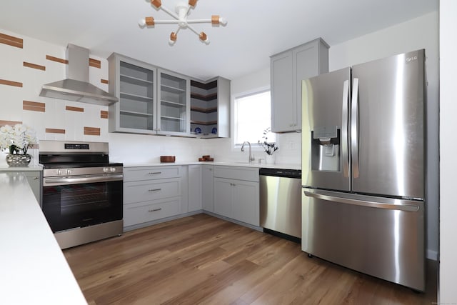 26 Riverdale Rd, Milford, CT 06460 - kitchen featuring stainless steel appliances, wall chimney exhaust hood, gray cabinetry, light countertops, and light wood finished floors