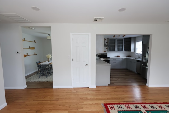 26 Riverdale Rd, Milford, CT 06460 - kitchen with stainless steel appliances, light wood-type flooring, light countertops, exhaust hood, and glass insert cabinets