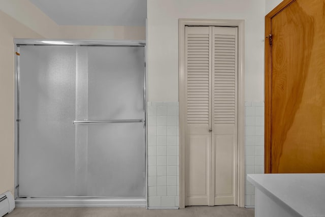 108 Sandelwood Dr, Madison, CT 06443 - bathroom with a closet, a stall shower, a baseboard radiator, tile walls, and a wainscoted wall