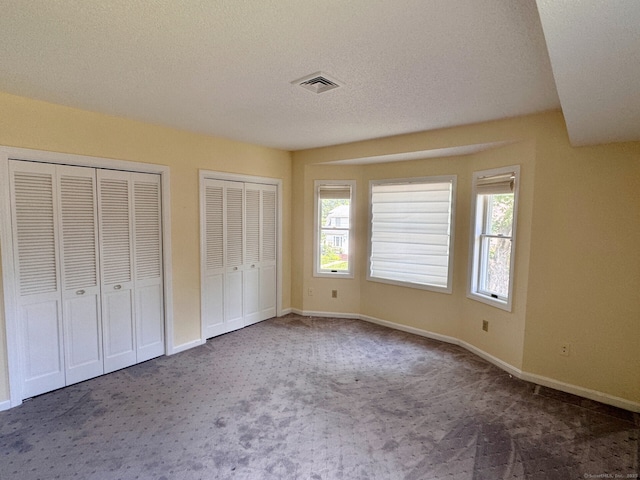 68 Wilson Ave Apt 103, Torrington, CT 06790 - unfurnished bedroom with carpet, two closets, and a textured ceiling
