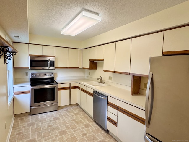 68 Wilson Ave Apt 103, Torrington, CT 06790 - kitchen with stainless steel appliances, a textured ceiling, light countertops, and brick patterned flooring