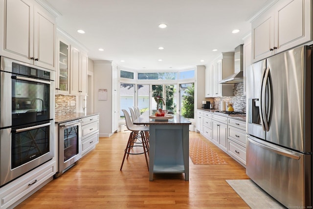 110 Westwood Rd, New Haven, CT 06515 - kitchen with appliances with stainless steel finishes, wall chimney exhaust hood, wine cooler, light wood-type flooring, and recessed lighting