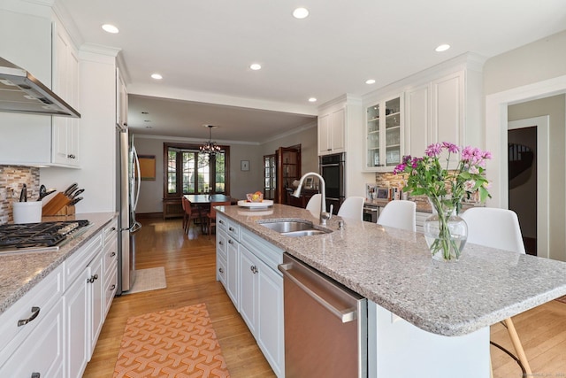 110 Westwood Rd, New Haven, CT 06515 - kitchen with stainless steel appliances, wall chimney exhaust hood, white cabinetry, light wood-type flooring, and ornamental molding