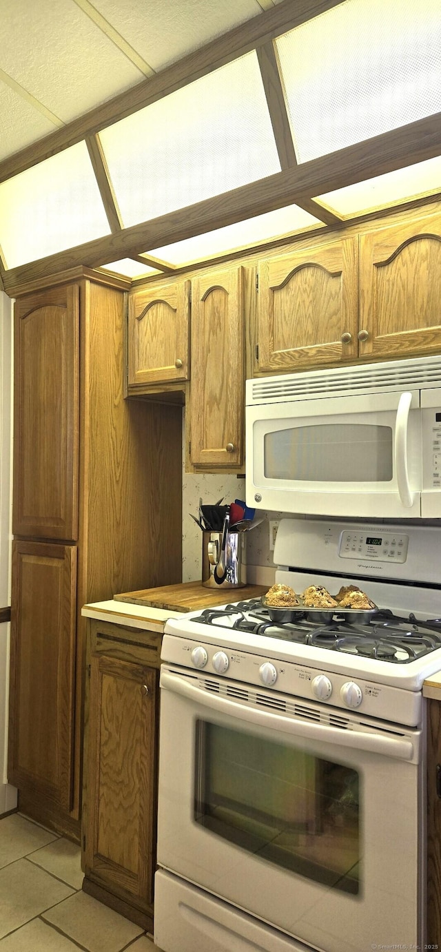 306 Old Colchester Rd Unit 197, Salem, CT 06420 - kitchen with white appliances, light tile patterned floors, and brown cabinetry