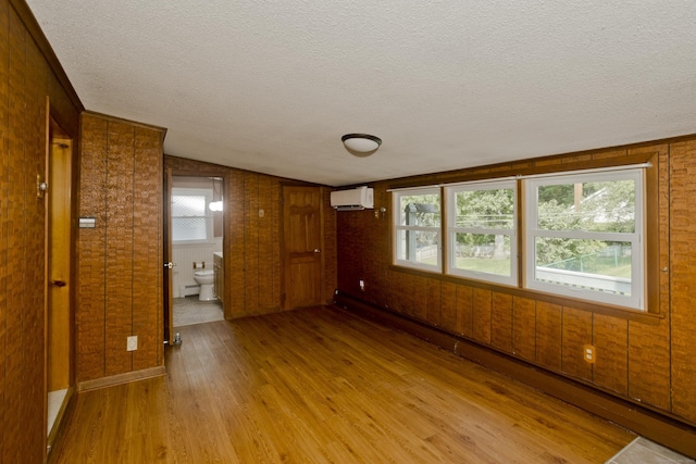 282 Halladay Dr, Suffield, CT 06093 - empty room featuring a wall mounted air conditioner, light wood-type flooring, a textured ceiling, plenty of natural light, and wooden walls