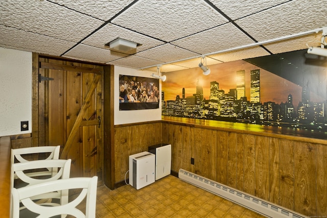 26 Sandpiper Rd, Enfield, CT 06082 - bar area featuring a baseboard radiator, tile patterned floors, wood walls, a wainscoted wall, and a drop ceiling