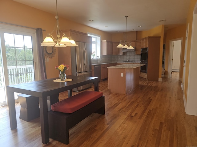 41 Mesa Dr, Bethany, CT 06524 - kitchen with stainless steel appliances, under cabinet range hood, a center island, decorative backsplash, and wood finished floors