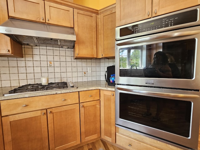 41 Mesa Dr, Bethany, CT 06524 - kitchen with stainless steel appliances, under cabinet range hood, decorative backsplash, light wood-type flooring, and light stone countertops