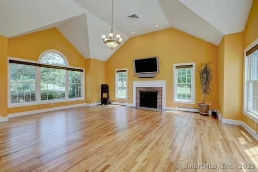 41 Mesa Dr, Bethany, CT 06524 - unfurnished living room featuring wood finished floors, a chandelier, vaulted ceiling, a brick fireplace, and plenty of natural light