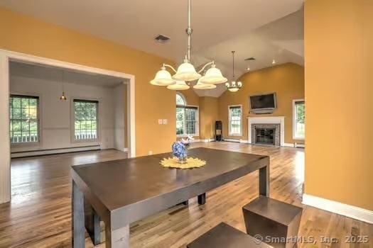 41 Mesa Dr, Bethany, CT 06524 - dining room with baseboard heating, a chandelier, wood finished floors, a fireplace, and vaulted ceiling