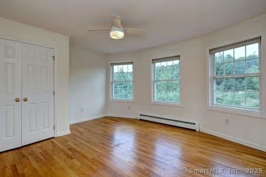 41 Mesa Dr, Bethany, CT 06524 - unfurnished bedroom featuring a baseboard radiator, wood finished floors, a closet, and a ceiling fan