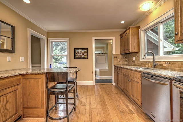 345 Spring St, Cheshire, CT 06410 - kitchen featuring stainless steel dishwasher, washer / dryer, light wood-type flooring, brown cabinetry, and light stone counters