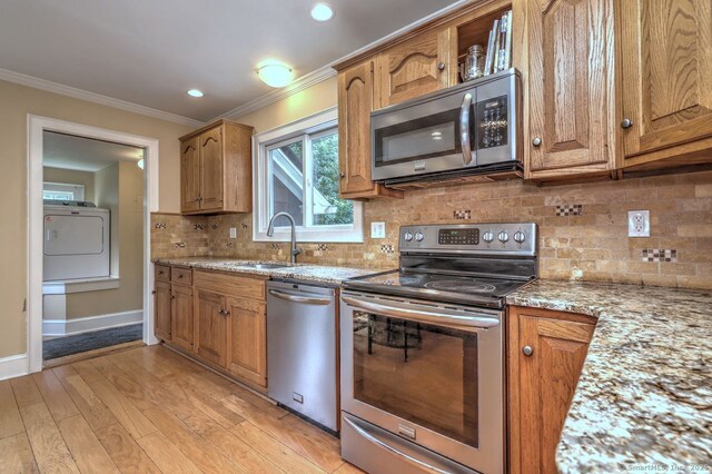 345 Spring St, Cheshire, CT 06410 - kitchen with appliances with stainless steel finishes, washer / dryer, crown molding, brown cabinets, and light stone countertops