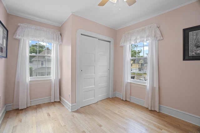 169 Peck Ave, West Haven, CT 06516 - unfurnished bedroom with light wood-type flooring, multiple windows, ornamental molding, a ceiling fan, and a closet