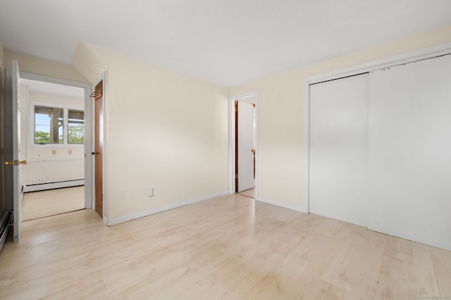 8 Griswold Dr, East Lyme, CT 06357 - unfurnished bedroom with baseboard heating, light wood-style flooring, and a closet