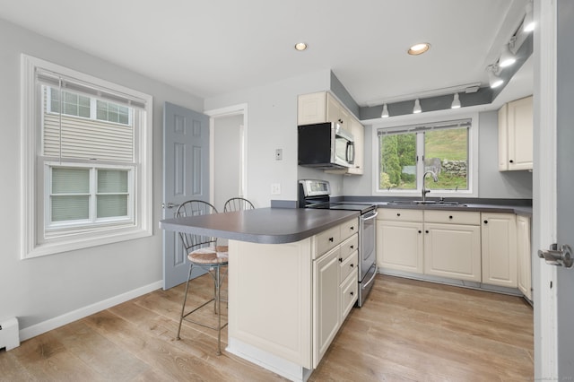 8 Griswold Dr, East Lyme, CT 06357 - kitchen with stainless steel appliances, dark countertops, a kitchen bar, a peninsula, and light wood finished floors
