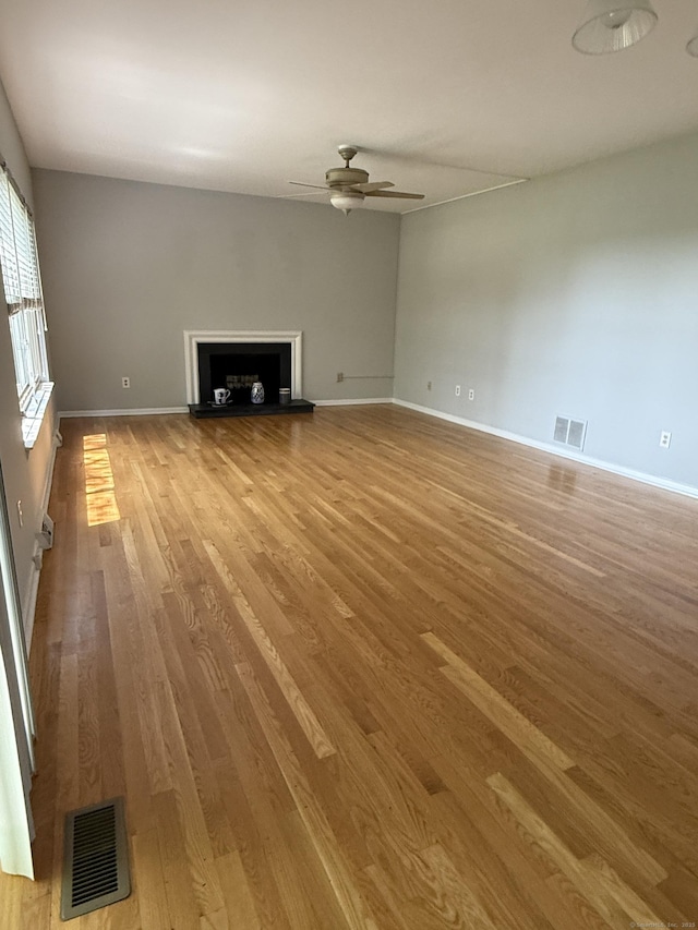 13 Hills Ln Unit 13, Westport, CT 06880 - unfurnished living room with wood finished floors, a ceiling fan, and a fireplace with raised hearth