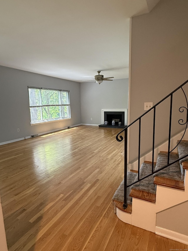 13 Hills Ln Unit 13, Westport, CT 06880 - unfurnished living room with a fireplace with raised hearth, wood finished floors, a ceiling fan, and stairs