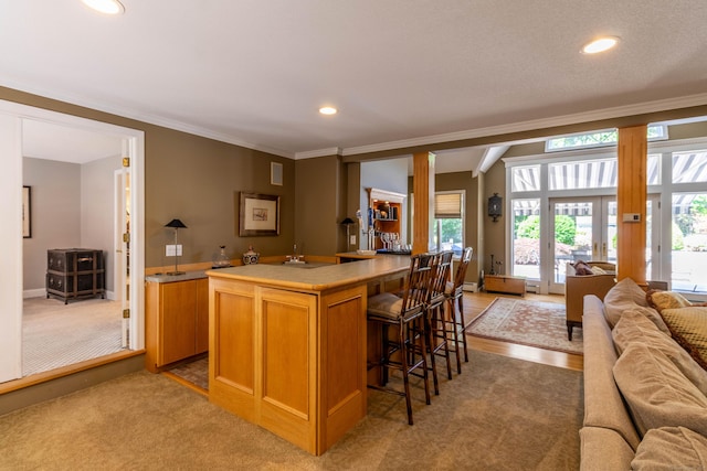 10 Brian Dr, Hebron, CT 06248 - kitchen featuring open floor plan, a kitchen breakfast bar, recessed lighting, crown molding, and light colored carpet