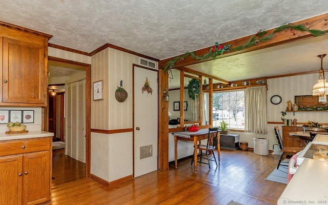39 Mohawk Ln, Wethersfield, CT 06109 - kitchen with wood finished floors, crown molding, a textured ceiling, light countertops, and brown cabinetry