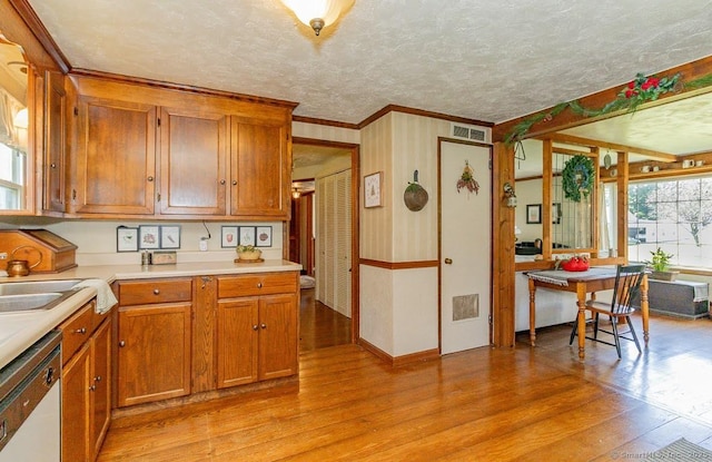 39 Mohawk Ln, Wethersfield, CT 06109 - kitchen with dishwasher, light wood finished floors, light countertops, crown molding, and brown cabinetry