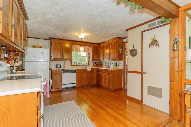 39 Mohawk Ln, Wethersfield, CT 06109 - kitchen with white appliances, crown molding, wood finished floors, light countertops, and brown cabinets