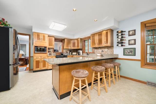 135 Harvest Woods Rd, Middlefield, CT 06481 - kitchen with stainless steel fridge, a peninsula, tasteful backsplash, a breakfast bar, and recessed lighting