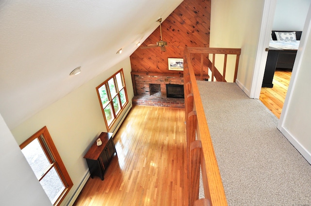11 Brianwood Ln, Granby, CT 06035 - unfurnished living room with a baseboard radiator, wood finished floors, wood walls, ceiling fan, and high vaulted ceiling