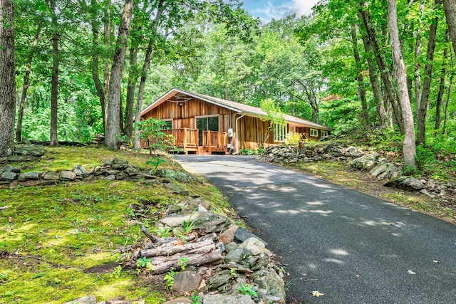 1037 Bartholomew Rd, Middletown, CT 06457 - rustic home featuring a wooden deck, driveway, board and batten siding, and a wooded view