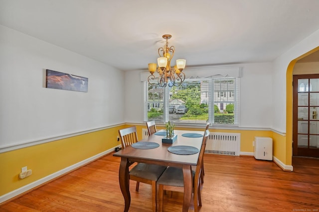 57 Lakeview Ave, Hamden, CT 06514 - dining area featuring wood finished floors, a chandelier, arched walkways, and radiator