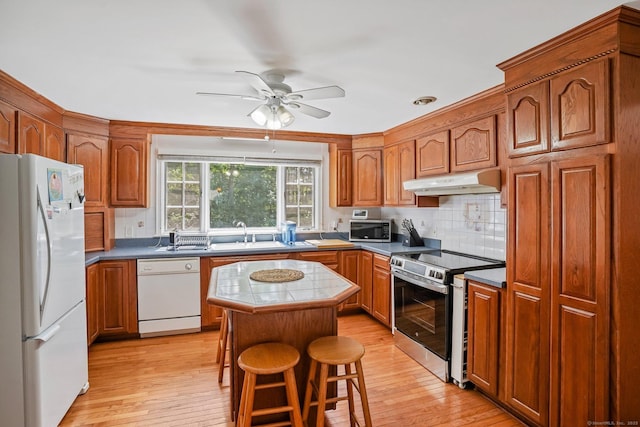 57 Lakeview Ave, Hamden, CT 06514 - kitchen featuring stainless steel appliances, under cabinet range hood, light wood finished floors, a kitchen island, and backsplash