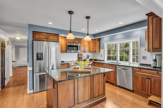 60 Ledgeview Ln, Guilford, CT 06437 - kitchen featuring stainless steel appliances, brown cabinetry, dark stone counters, light wood-style floors, and decorative light fixtures